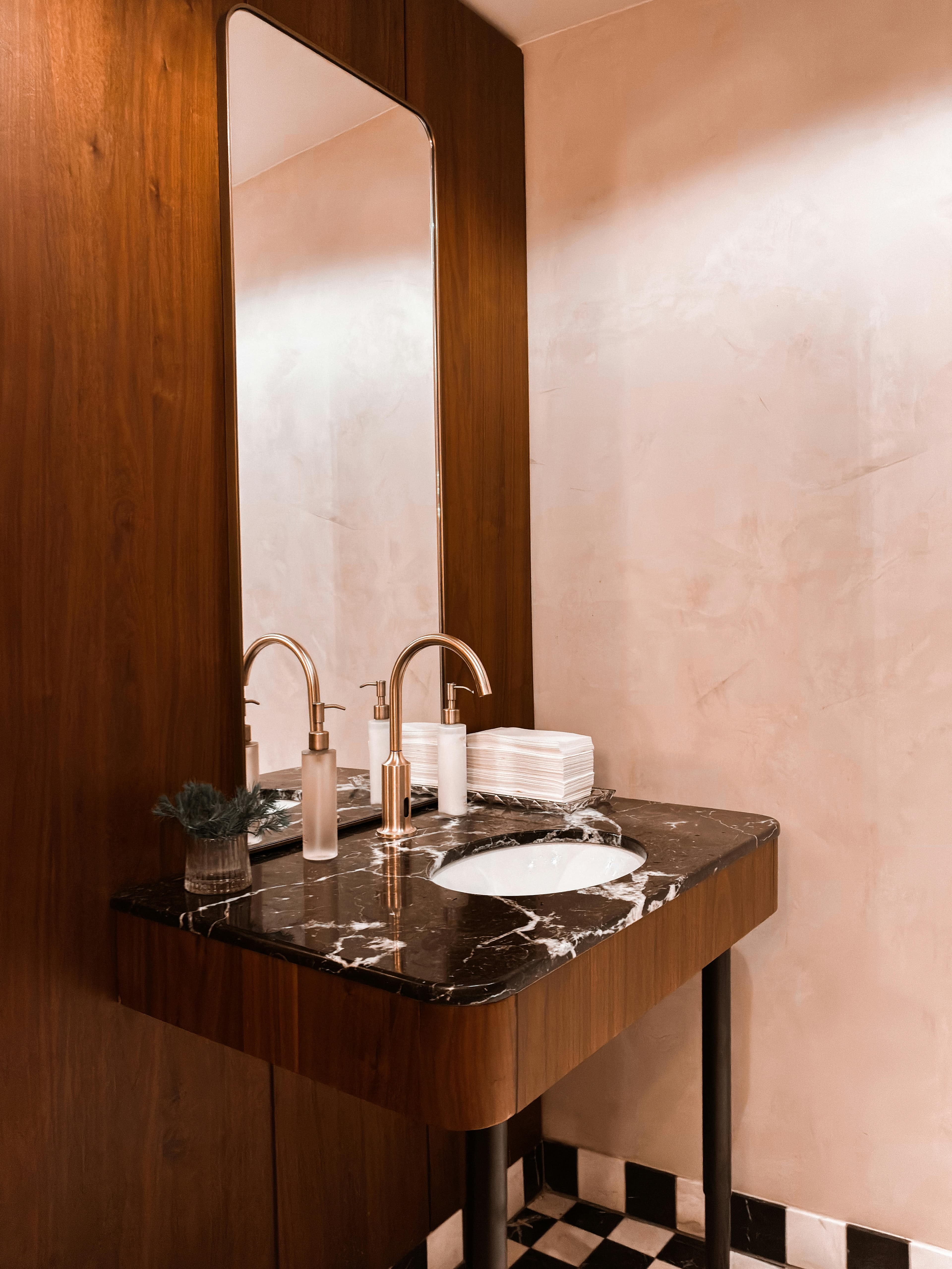 Elegant luxury restroom trailer vanity with marble countertop, brass fixtures, and mirror at an upscale event